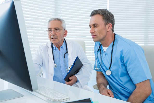 Surgeon and doctor collaborating on computer in clinic. Ideal for illustrating medical teamwork, healthcare technology, professional consultations, and patient care in hospital settings. Useful for medical websites, healthcare blogs, and educational materials.