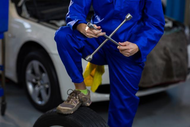 Mid-section of female mechanic with lug wrench - Download Free Stock Photos Pikwizard.com