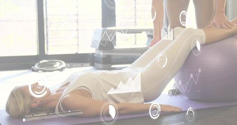 Trainer assisting client stabilizing legs on stability ball for core balance and rehab