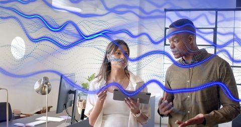 Colleagues collaborating over tablet with blue analytics waveform overlay in modern office