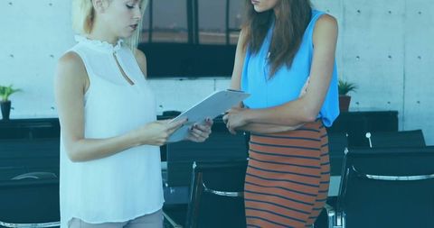 Two Businesswomen Reviewing Clipboard Document in Modern Office