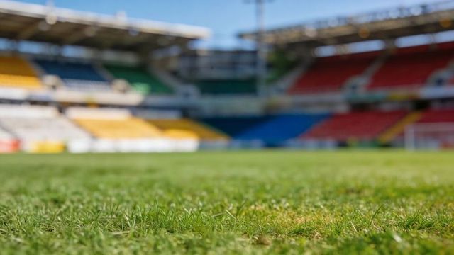 Low-angle closeup showing stadium turf texture with colorful empty stands and goal frame