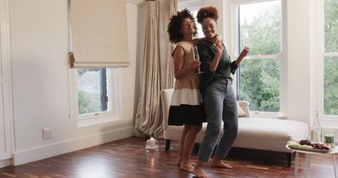 Joyful Same-Sex Couple Dancing at Home with Champagne