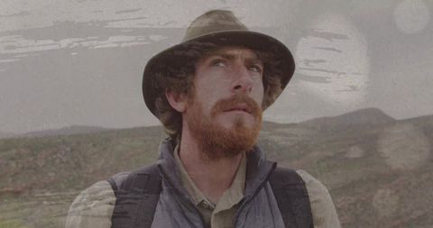 Backpacker scanning horizon with folded map, film grain overlay, outdoor explorer