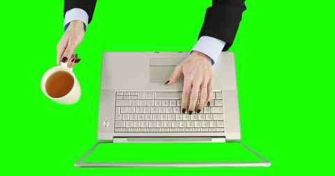 Caucasian person typing on laptop while holding coffee cup