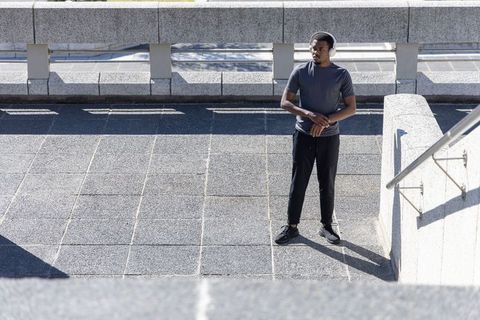 African american man standing on urban concrete terrace wearing headphones and athletic wear