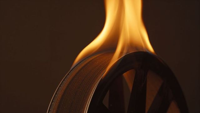 Burning film reel emitting intense flames in dark studio