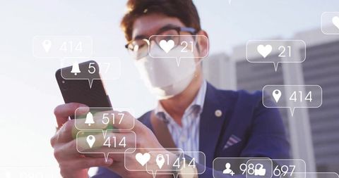 Businessman wearing mask tapping smartphone with floating social media notifications