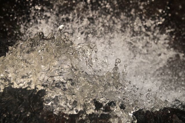 High-detail close-up capturing motion of water droplets splashing dynamically. Ideal for use in nature documentaries, water-themed advertisements, or backgrounds requiring a sense of fresh, energetic motion.