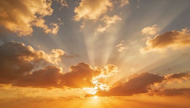 Glowing sunburst breaking through cumulus clouds at sunset radiating golden sunbeams