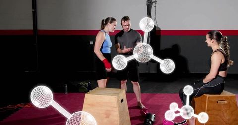 Fitness coach training two athletes with kettlebell and plyo boxes with molecular overlay