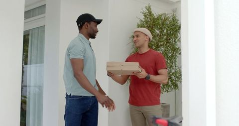 Delivering pizza on minimal porch: diverse male courier handing takeout boxes to customer