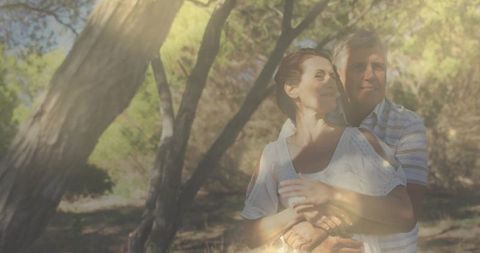 Senior Couple Embracing in Sunlit Forest Glade