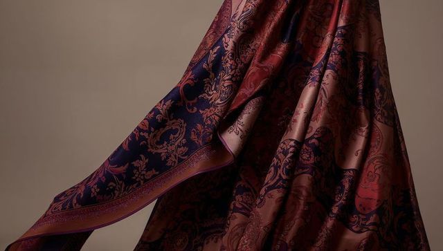 Luxurious draped silk scarf with ornate paisley pattern and rich jewel-tone satin sheen