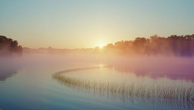 Misty Dawn Over Tranquil Lake with Reflecting Sunlight