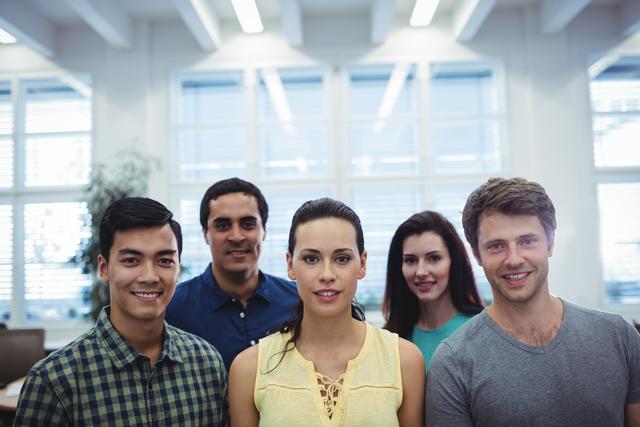 Diverse group of business executives smiling at camera in a modern office. Ideal for use in corporate websites, business presentations, team-building materials, and professional networking platforms to convey teamwork, diversity, and a positive work environment.