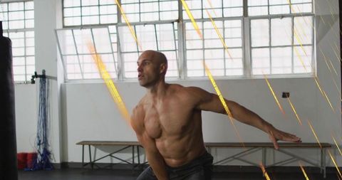 Twisting shirtless athlete extending right arm during boxing training in gym studio with gold lines
