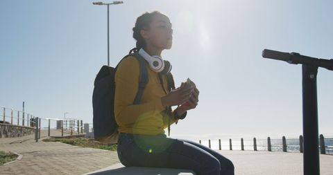 Digital nomad eating sandwich by the seaside promenade