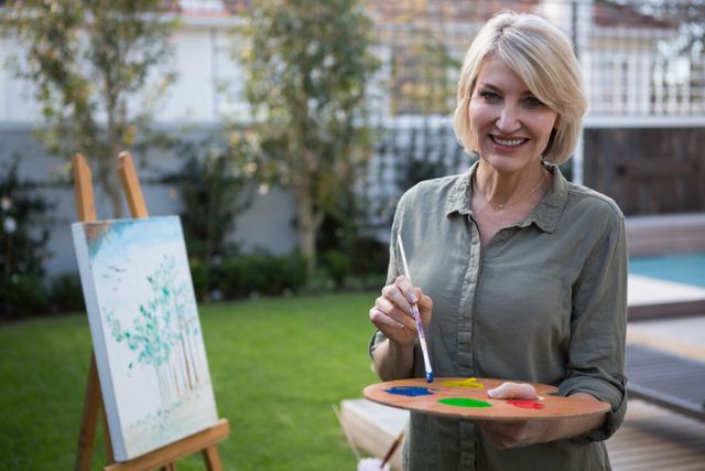 Portrait of happy woman holding palette and paintbrush