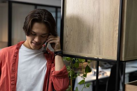 Young asian man making phone call in modern coworking space, casual professional moment
