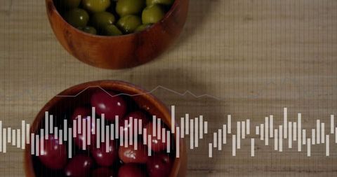 Wooden bowls with green and red olives on kitchen tabletop