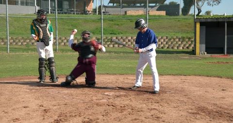 Male Baseball Players Competing at Home Plate on Sunny Field