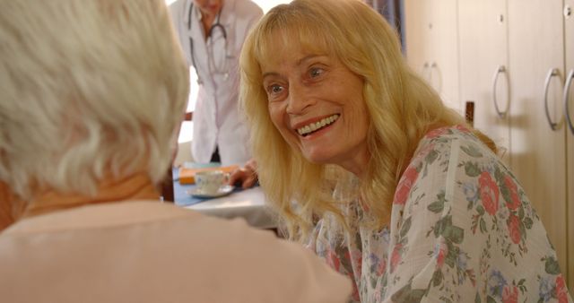 Smiling Elderly Woman Chatting in Nursing Home with Caregiver in Background - Download Free Stock Images Pikwizard.com