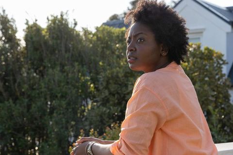 African american woman sitting on porch looking reflective backlit garden portrait