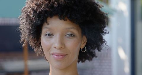 Smiling african american woman portrait in soft daylight with gold hoop earrings and afro