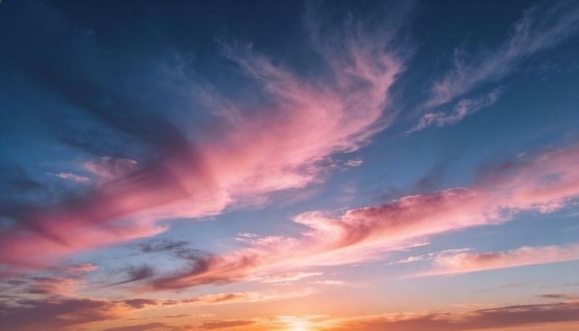 Pastel sunset sky with flowing pink cirrus clouds stretching across calm twilight horizon