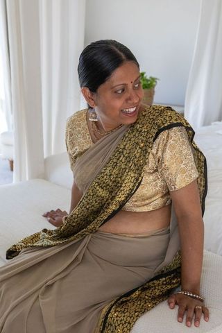 Elegant mature indian woman in traditional saree sitting in bedroom