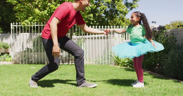 Happy biracial father and daughter dancing in garden together. domestic lifestyle, spending free time at home.