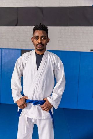Martial Artist Standing Confidently in Dojo Wearing Gi and Blue Belt
