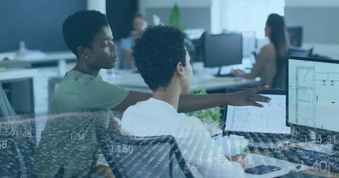 Professional Women Analyzing Building Plans in Modern Office