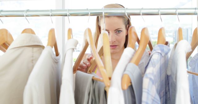 Attractive fashion designer looking at clothes on rail in her studio
