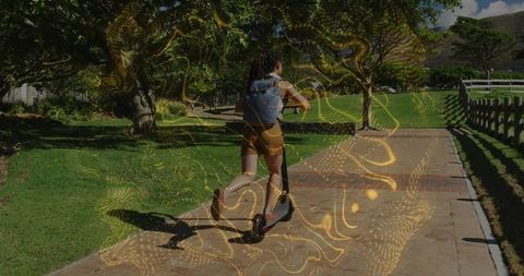 Woman riding electric scooter in park with golden light trails