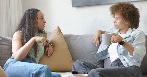 African American Women Chatting on Couch Over Coffee Cozy Living Room Conversation