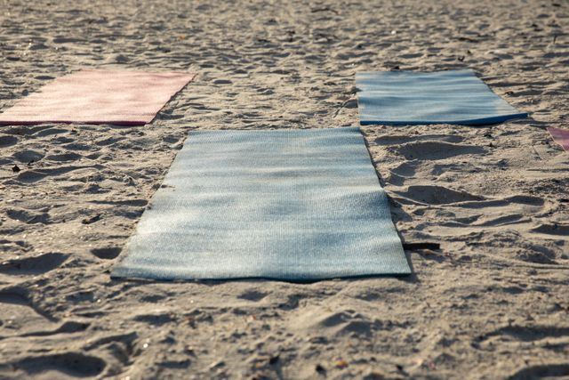 Close up of three colorful yoga mats on the beach by the sea on a sunny day.