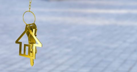 Golden house keychain on blurred background depicting luxury