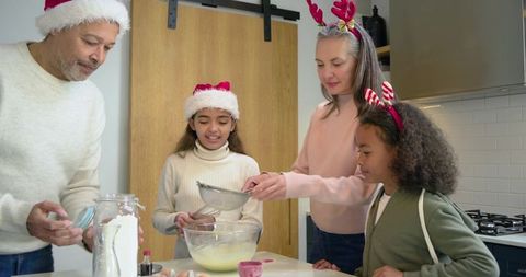 Multicultural family baking holiday treats together in modern kitchen mixing and sifting batter
