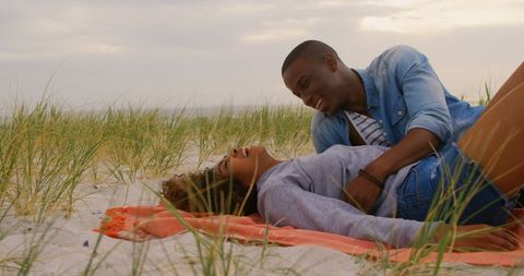 Joyful Couple Relaxing on Sandy Beach Grass