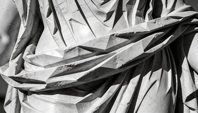 Revealing carved marble drapery with angular pleats and chisel marks, classical sculpture detail