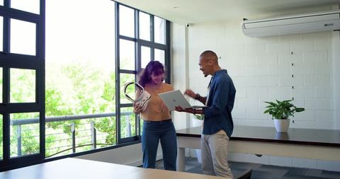 African american coworkers collaborating over laptop and headset in modern bright office