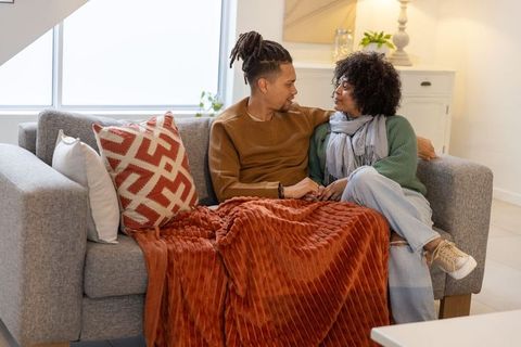 African american couple relaxing on sofa under cozy rust throw sharing intimate moment