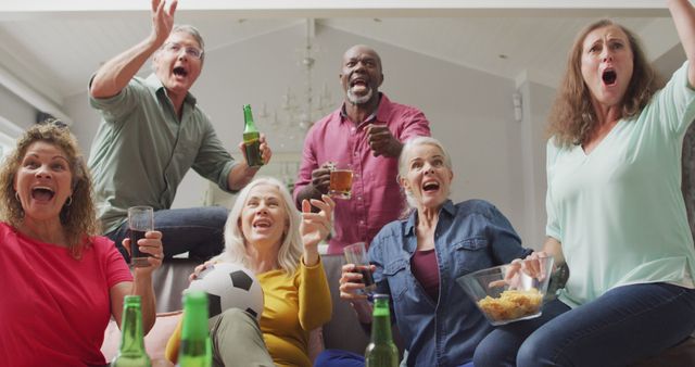 Group of middle-aged friends are watching a sports game in the living room, showing excitement and enthusiasm. Perfect for use in advertisements, social media posts, or articles about friendship, sports events, or home gatherings.