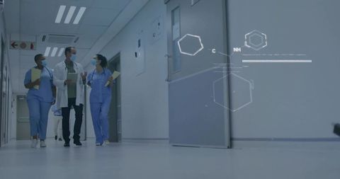 Medical team walking and discussing charts in corridor with digital healthcare overlay