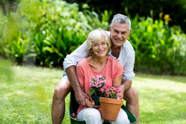 Senior couple enjoying gardening together in their yard. They are smiling and holding flower pots, showcasing their love and bond. Ideal for use in advertisements promoting healthy lifestyles, retirement communities, gardening products, and family bonding activities.