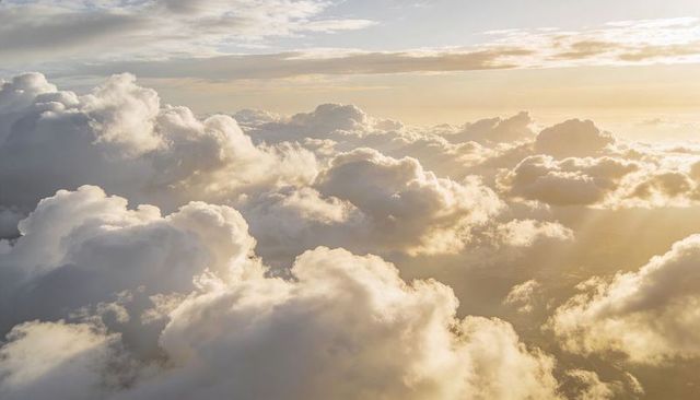 Golden Sunbeams Streaming Through Towering Cumulus Clouds from Aerial High-Altitude View