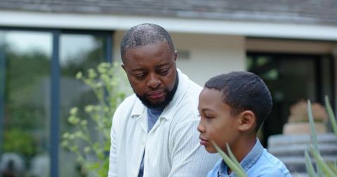 Father and son having quiet conversation on garden patio during reflective parenting moment