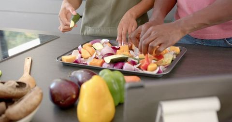 Couple Preparing Fresh Vegetables on Baking Tray in Kitchen